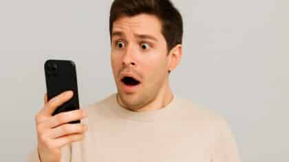 Un homme surpris lit un message d’alerte extrême sur son smartphone.