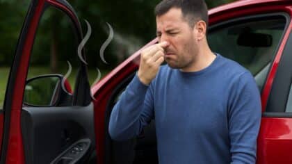 Un homme qui ouvre la portière de sa voiture et réagit à une forte mauvaise odeur à l’intérieur.