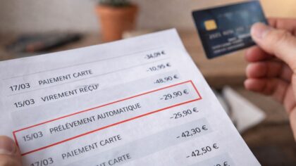 Mains tenant un relevé bancaire, illustrant une dépense mensuelle régulière rarement remise en question