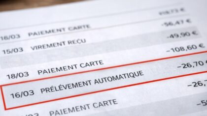 Personne consultant un relevé bancaire sur une table, illustrant une ligne de dépense répétée et souvent ignorée